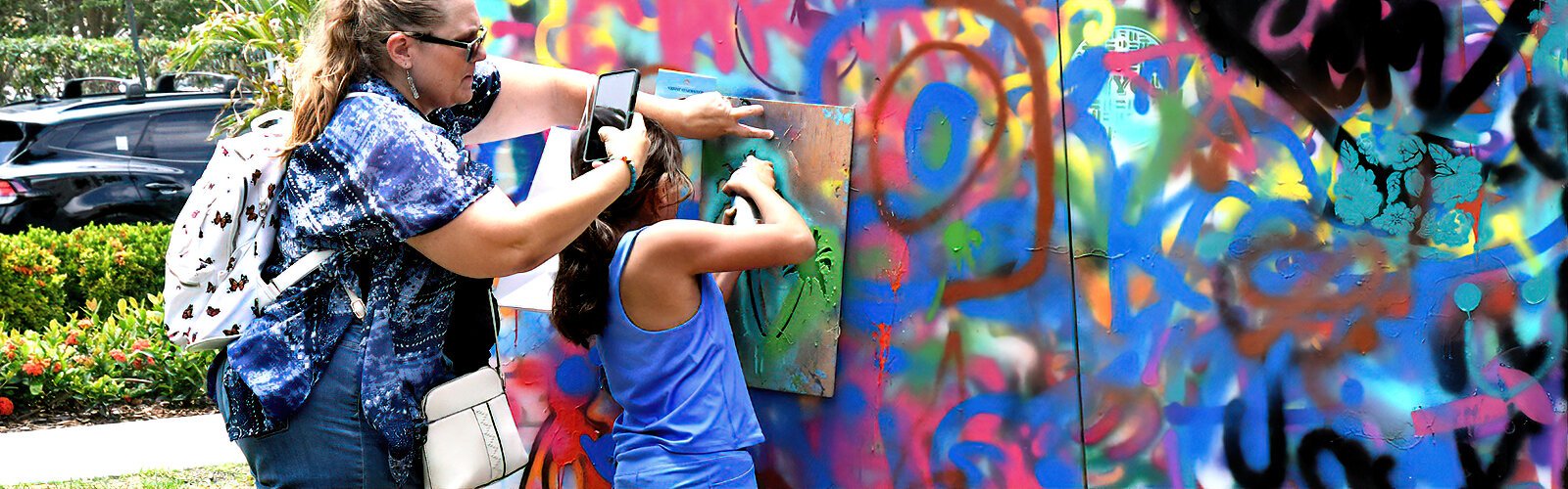Stacey Diaz of Pinellas Park holds a stencil for her daughter Hazel, 8, who is spray-painting at the Overspray Art Space station.