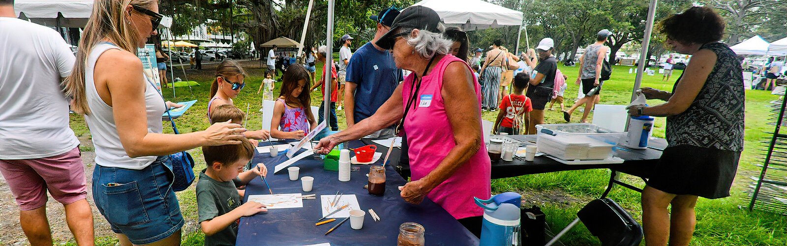 At this Painting in the Park station, MFA volunteer Eileen helps children discover the peculiar art of painting with cacao water.