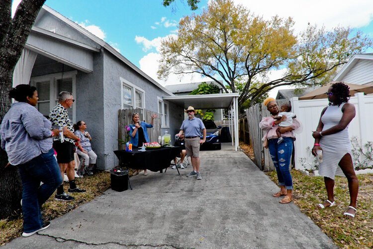 The historic tour stops at a former Doby home on Azeele Street where they are greeted by present owner Tara Nelan. Ernest Doby’s great-great-grand-daughters Jasmine and Zoe, who is holding her son Frederick, have joined the tour and listen.