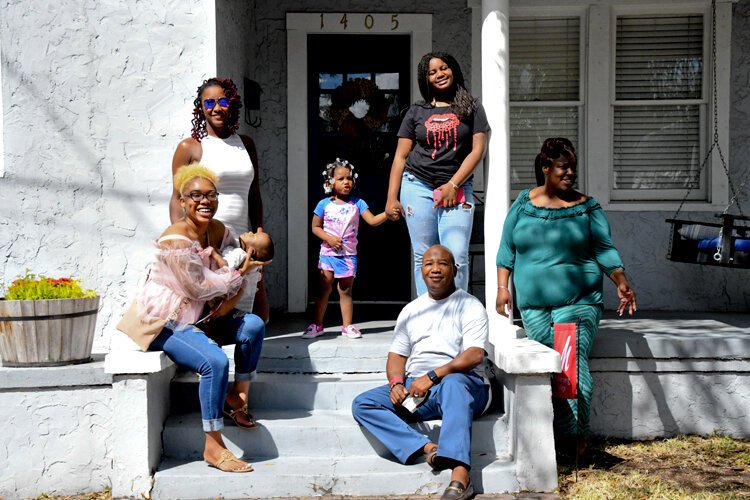 Harold Doby Jr., his daughters Jasmine and Zoe, who is holding her son Frederick, other family members and a friend, pose in front of a former Doby family home on Azeele Street.