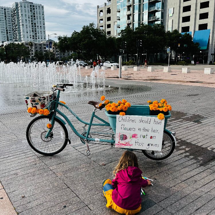 Maya Rabaut, age 5, colors a sign that reads, “Children should have flowers in their hair, not on their graves.”