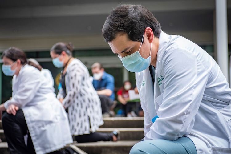 Healthcare workers kneel in honor of #whitecoatsforblacklives.